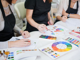 Professional makeup courses. Cropped shot of ladies studying colors, using paint and brushes.