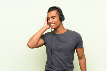 Fototapeta premium Young handsome man listening music with a mobile over isolated green wall
