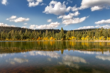 Fototapeta na wymiar Pristine view of a mirror lake on a crisp autumn day with mountains and fall foliage.