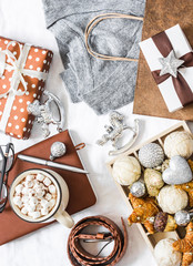 Christmas mood background. Festive Christmas shopping concept. Grey cashmere pullover, gift box, notepad, christmas decorations, hot chocolate with marshmallow on white background, top view. Flat lay