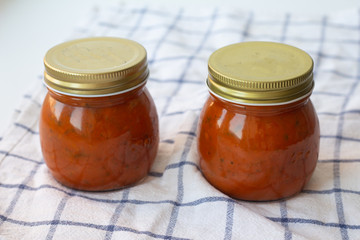 tomato sauce with herbs in a jar on a white towel