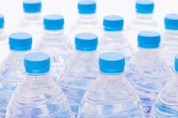Rows of plastic bottles. Necks of plastic bottles of still water with blue caps, close up