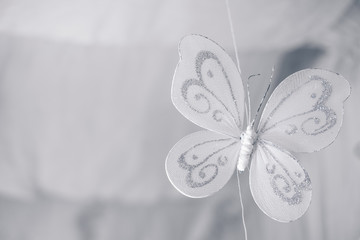 Close up of a hanging handmade white butterfly with silver glitters made from sheer materials. Selective focus. Copy space at the left.