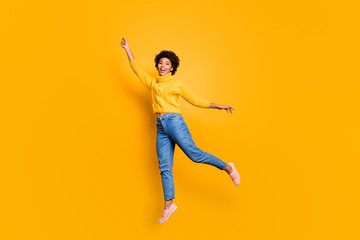 Fototapeta na wymiar Full length body size photo of curly charming pretty sweet girlfriend feeling free wearing jeans denim yellow sweater footwear jumping up flying away isolated vivid color background
