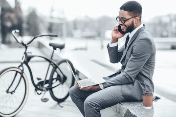 Businessman with bicycle nearby having business talk on phone
