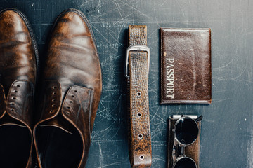 Leather accessories, brown shoes, passport cover, belt and sunglasses. Travel concept.