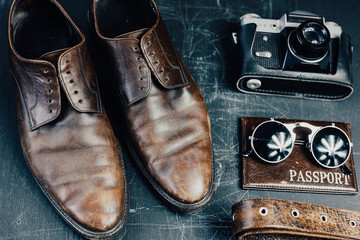 Fototapeta na wymiar stylish leather accessories, brown shoes, a camera, a passport, sunglasses. Travel concept