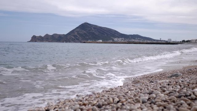 View at ground level of the beach with stones of Altea, Mediterranean sea in the province of Alicante. A sunny summer day.
