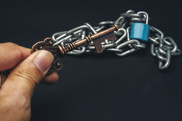 Fototapeta na wymiar A man's hand holding an old key with a chain with a background.