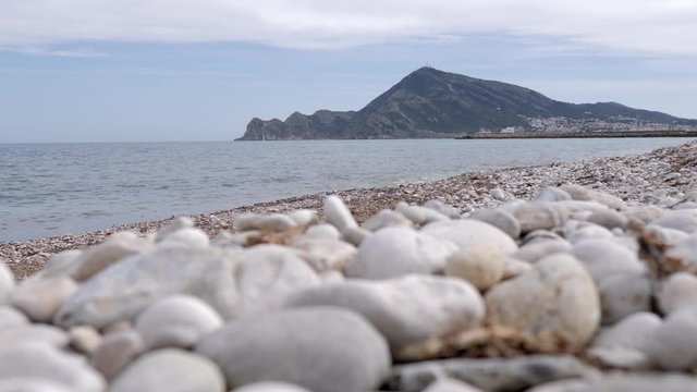 View at ground level of the beach with stones of Altea, Mediterranean sea in the province of Alicante. A sunny summer day.