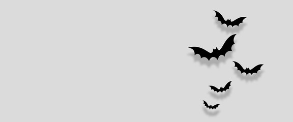 Black paper bats flying over white background. Halloween concept. Flat lay