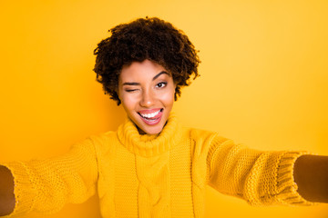 Photo of curly wavy cheerful charming attractive girlfriend licking her lips blinking taking selfie isolated over yellow vivid color background
