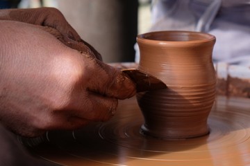 The potter teaches the child how to form a clay jug on a potter's wheel.