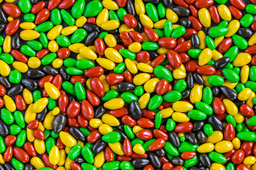 Background in the form of milk chocolate in multi-colored glaze in the form of small sweets