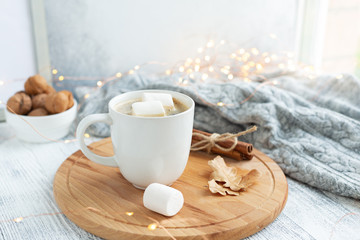 Obraz na płótnie Canvas Mug with coffee and marshmallow, sweater, cinnamon, decorated with led lights. Autumn mood. Cozy autumn composition. Hygge concept Soft focus - Image