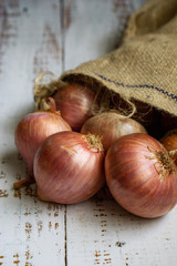 Fresh raw bombay onions or red onions on wooden background.