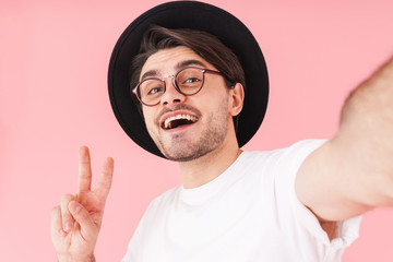 Image of smiling man wearing eyeglasses and hat taking selfie photo
