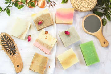 handmade multicolored soap with herbs and rosebuds, comb, towel, mirror, face brush on a marble...