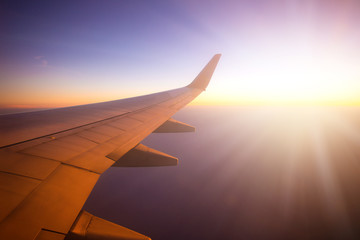 Naklejka na ściany i meble Airplane wing with sunrise in light flare