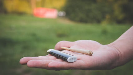 Close-up of males hands holding marijuana joint, smoking cannabis blunt outdoors.