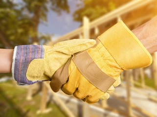 Building, teamwork, partnership, gesture and people concept - close up of builders hands in gloves...