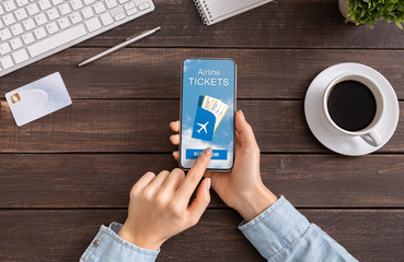 Woman booking airline tickets online with app on smartphone