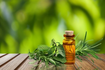 Oil bottle and green herbs on blue background