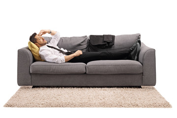 Businessman resting on a sofa bed after work