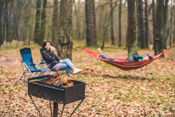 people resting outdoors. grill with fire close up. laying on hammock on background