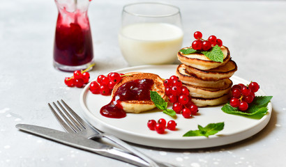 family breakfast pancakes gluten free with cherry jam and fresh berries,  two plates of pancakes, milk in round glasses.