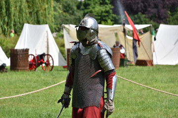 Knight in a chainmail with a sabre and lobster-tailed pot helmet. Historical reenactment of a medieval knight fights in Brodnowski park in Warsaw, Poland - 290306939