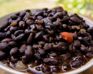 black beans in soup, served in a deep plate on a wooden table