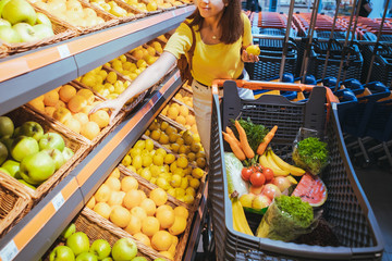 woman taking oranges from supermarket store shelf