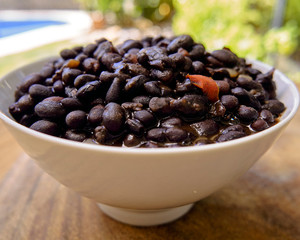 black beans in soup, served in a deep plate on a wooden table