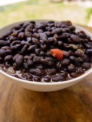 black beans in soup, served in a deep plate on a wooden table