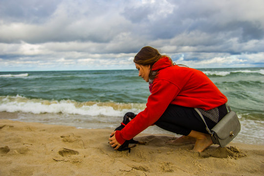 Piesek pinczer miniaturowy ratlerek bawi się z dziewczyną na plaży nad morzem