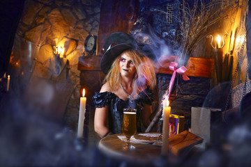 The witch is conjuring  by the candlelight. The dark room, smoke.