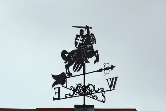 Weathervane in the form of a crusader with a horse with a sword in his hand. A product made of metal on the roof of the house.