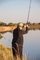 Fisherman fishes spinning on the river bank