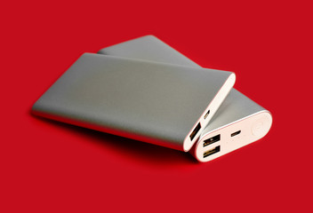 Power bank for charging mobile devices. White smart phone charger with power bank. Battery bank on a red background . External battery for mobile devices.