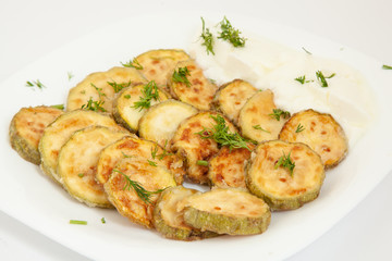Fried zucchini with yogurt in white plate.