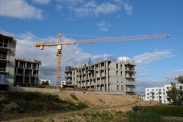 New apartment building place - unfinished  houses, cranes, construction equipment and silhouettes of workers at work.