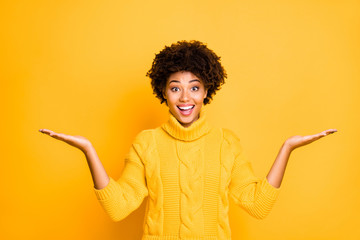 Photo of dark skin sales lady holding two new products on arms proposing best prices wear warm...