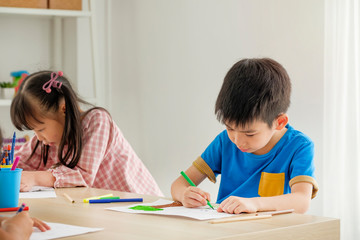 Children drawing with color pencils in playroom