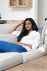 Person of color, possibly Indian, Mexican or African American, lounging in a modern farmhouse interior