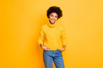 Photo of dark skin funny lady in good mood wear warm knitted pullover and jeans standing isolated yellow color background