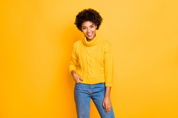 Photo of dark skin funny lady in good mood wear warm knitted pullover and jeans standing isolated yellow background
