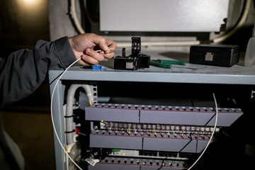 The technician attaching fiber optic on the Optical Distribution Frame. Man working in network server room with fiber optic hub for digital communications and internet.