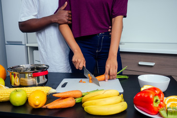 Happy african american love couple cooking fruits salad at kitchen