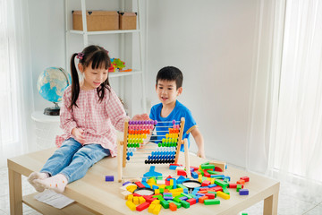 Children playing abacus and wooden block toy in playroom